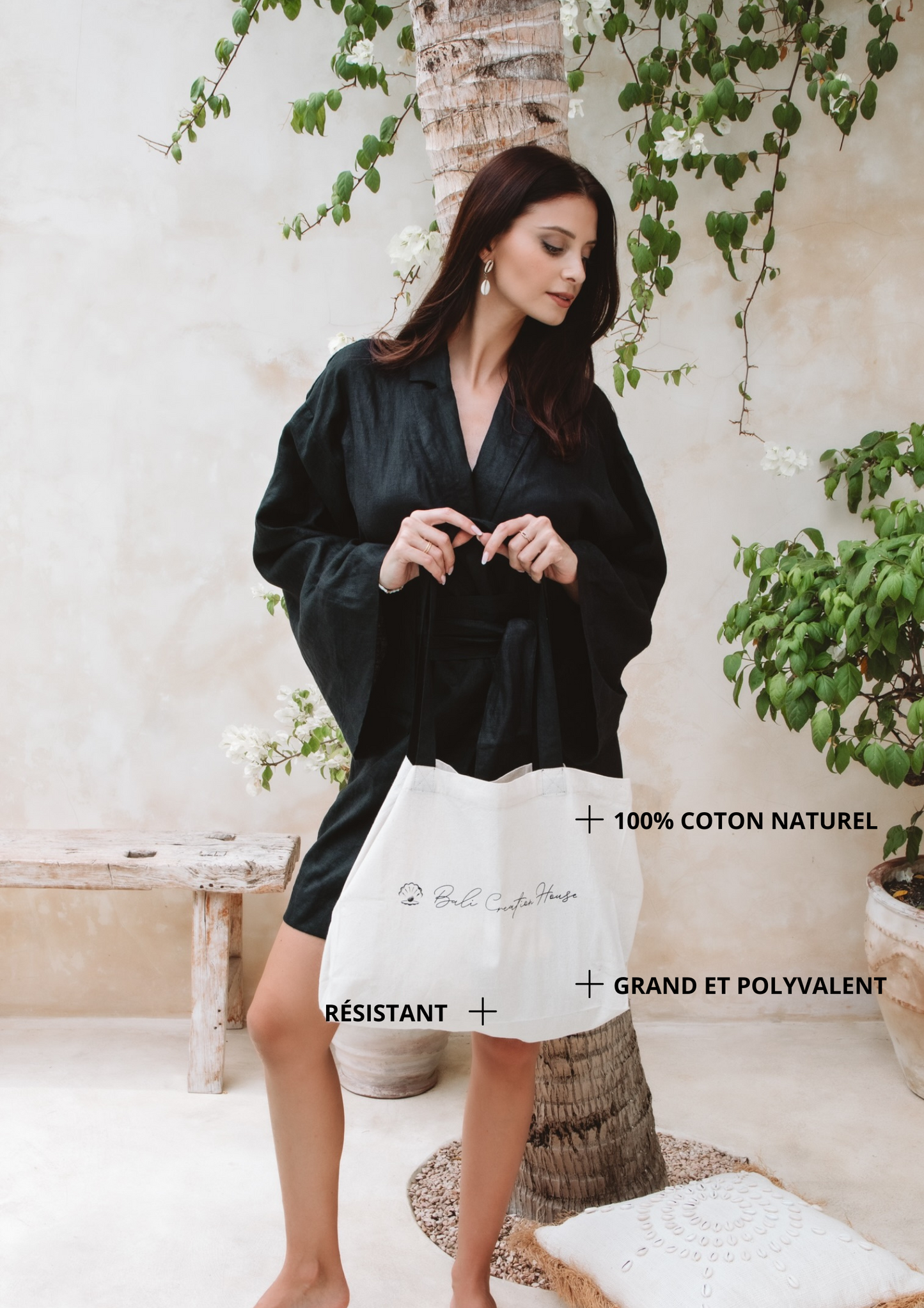 Femme portant un sac en coton blanc à anses noires dans un jardin au style épuré